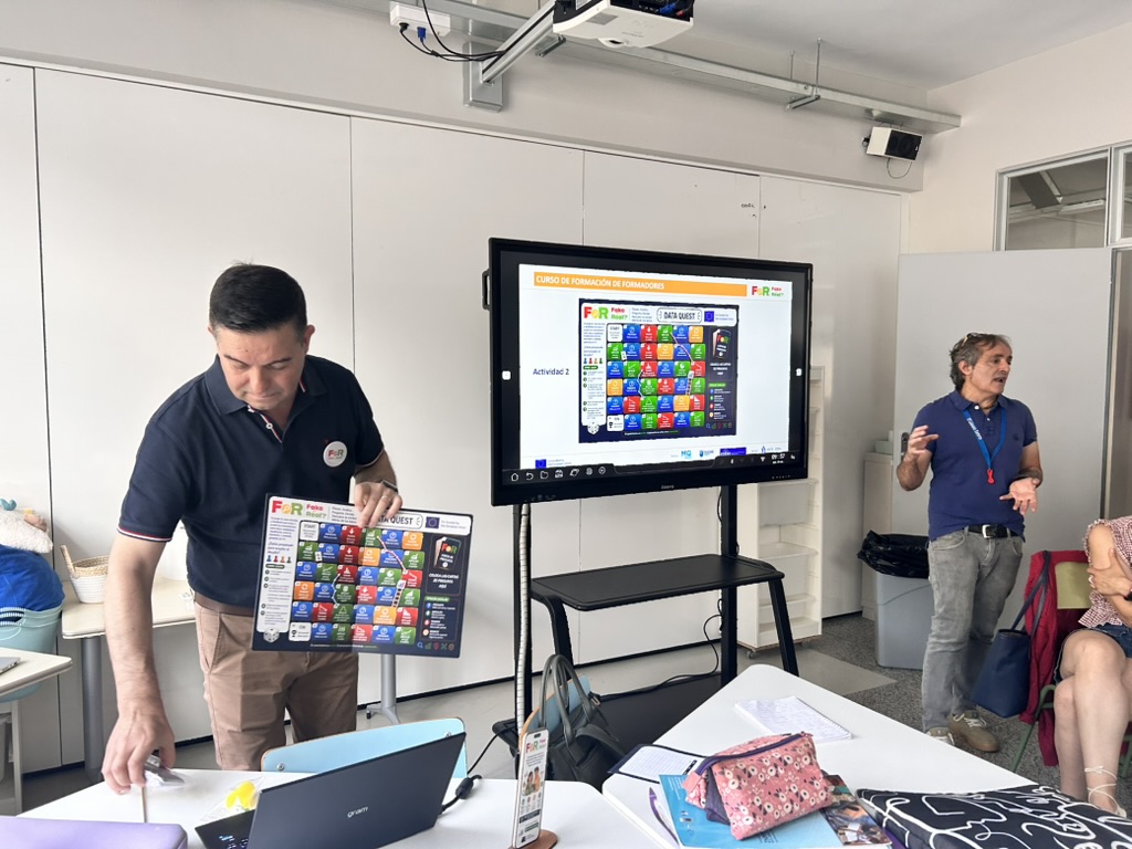 Apresentação de materiais de formação, com um quadro de atividades e participantes numa sala.